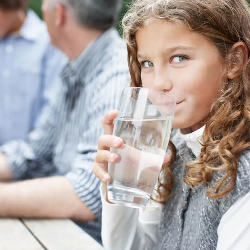young girl drinking clean purified water out of a glass