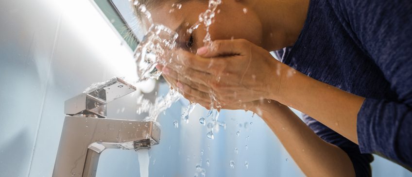 a woman washing her face in the sink