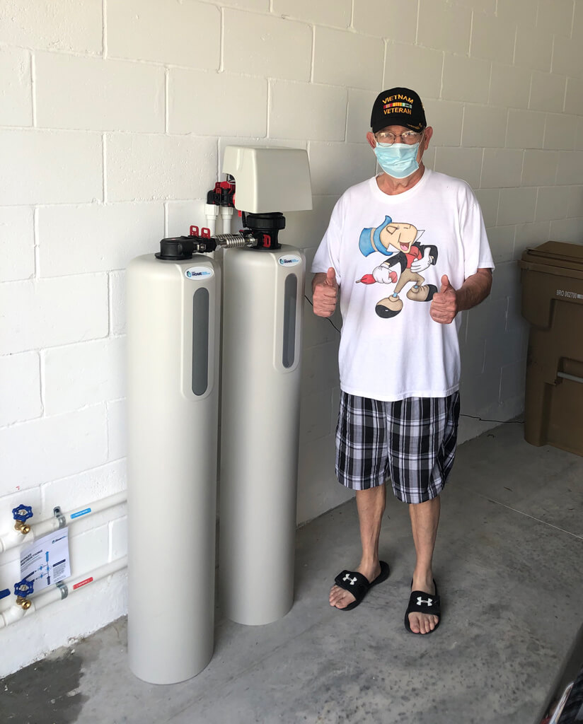 customer with a safety mask celebrating his appreciation alongside a newly installed water filtration system