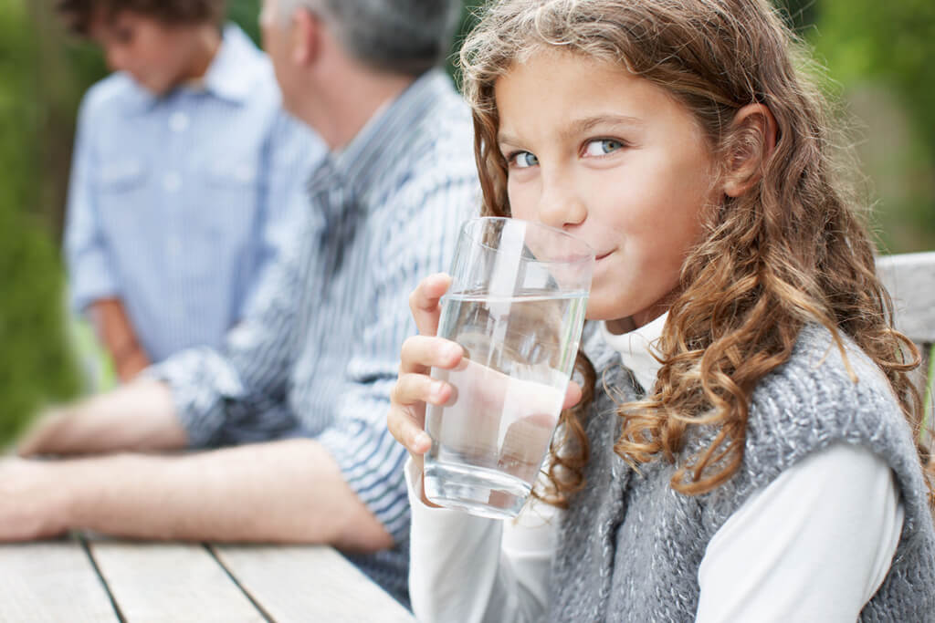 young girl drinking clean purified water out of a glass